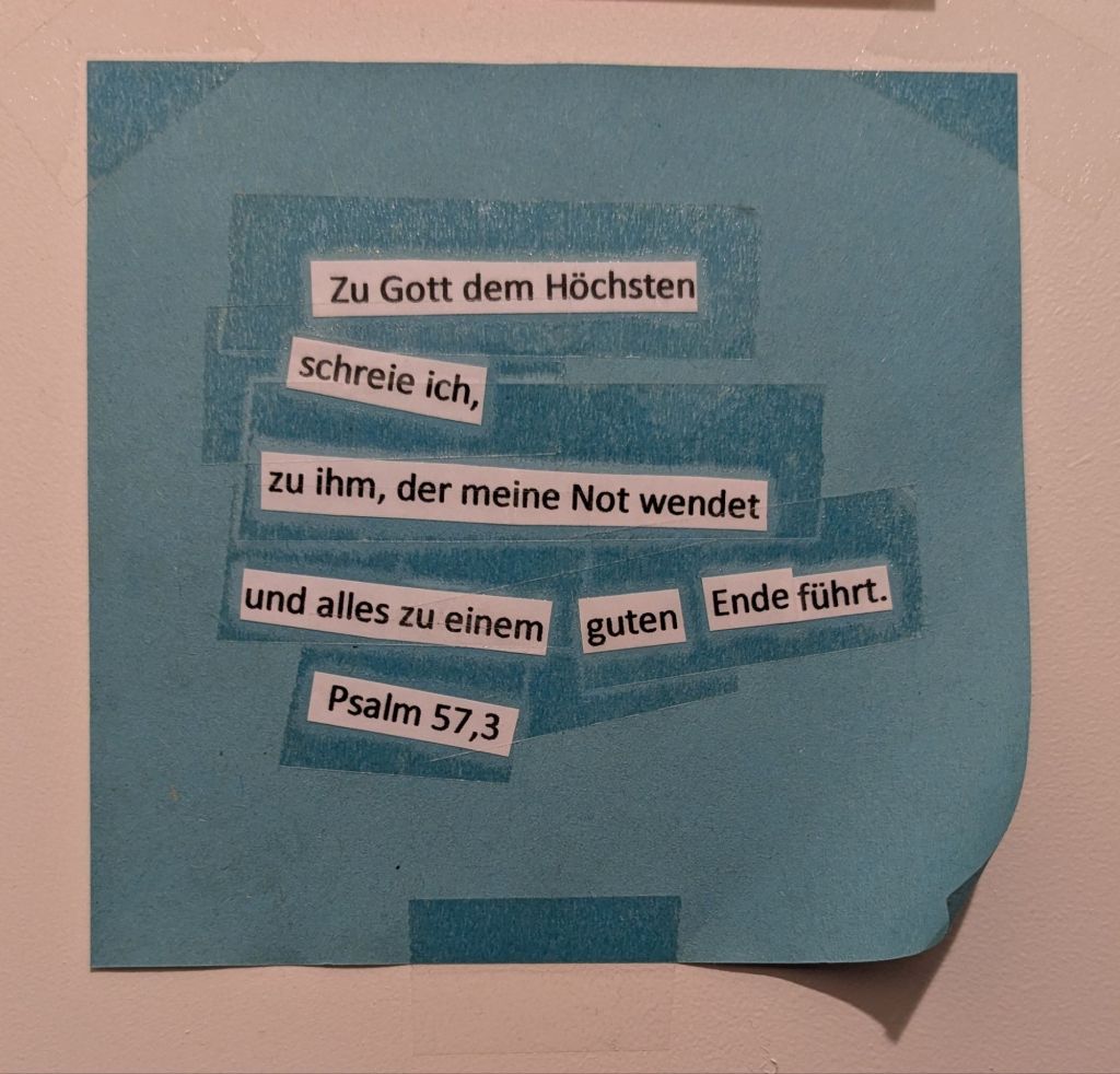 Hellblauer quadratischer Zettel auf weißem Hintergrund, der Zettel hat rechts unten ein Eselsohr. Auf weißen schmalen Streifen die folgenden Wörter, in diese Stücke geteilt:
Zu Gott dem Höchsten 
schreie ich, 
zu ihm, der meine Not wendet 
und alles zu einem 
guten 
Ende führt. 
Psalm 57,3